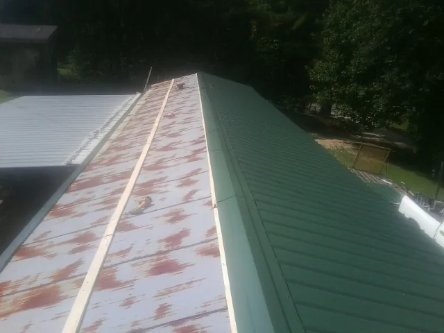 Old rusted panels beside newly installed green metal roofing — Wind Damage Roof Repair by Roofing Brothers in Cripple Creek