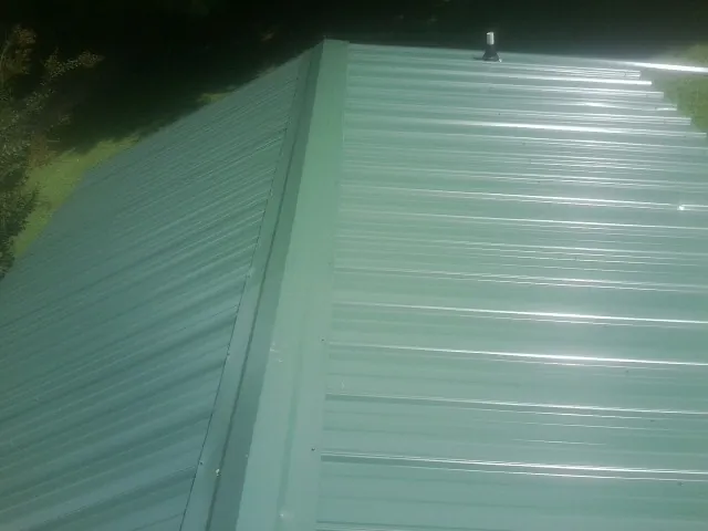 New green metal panels meeting at the ridge of a roof — Flat Roof Repair work by our crew in Cripple Creek