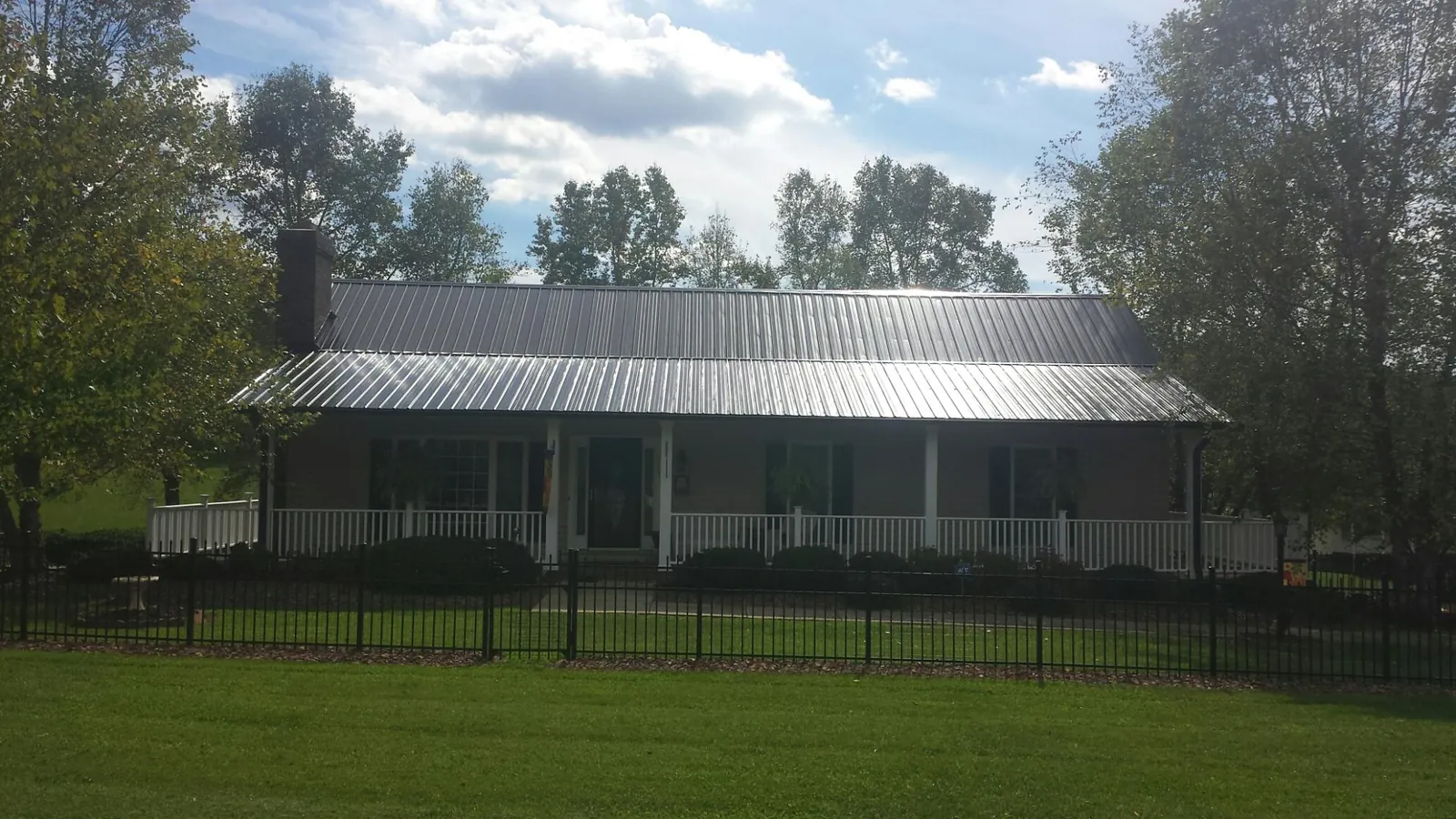 Gray metal roof on a brick ranch with a full width front porch — Gutter Guard Installation work by our crew in Cripple Creek