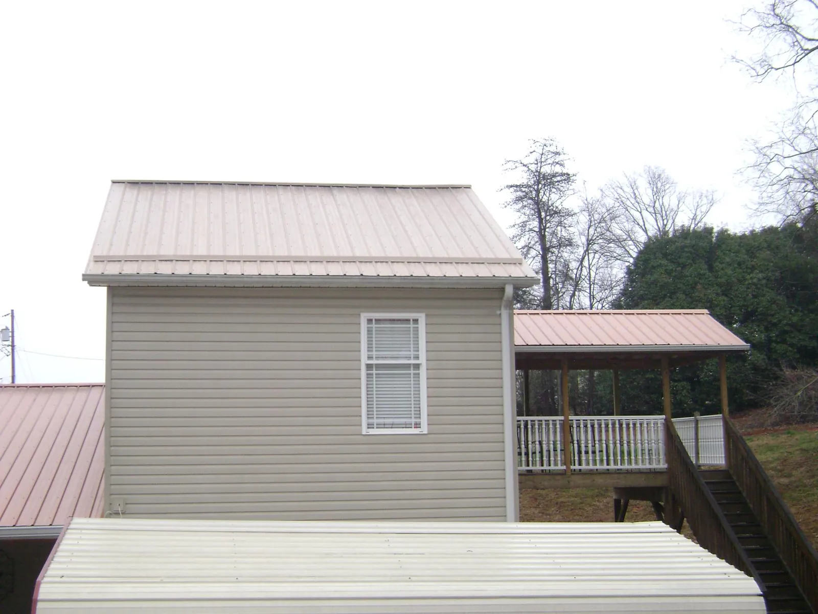 Tan metal roofs on a two story addition and attached porch, from a Roof Replacement job in Cripple Creek
