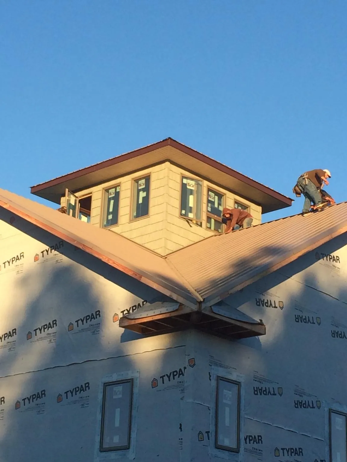 Roofers working around a rooftop cupola on a new metal roof at sunset — Roof Waterproofing in Cripple Creek by Roofing Brothers